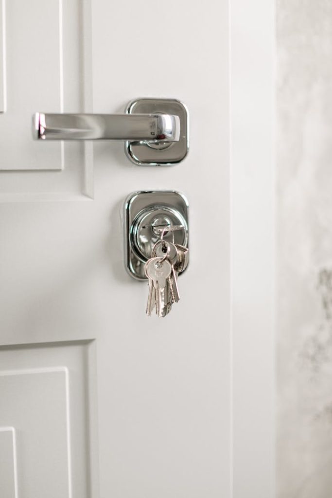 Close-up of a modern silver door handle with keys hanging in the lock, symbolizing security.